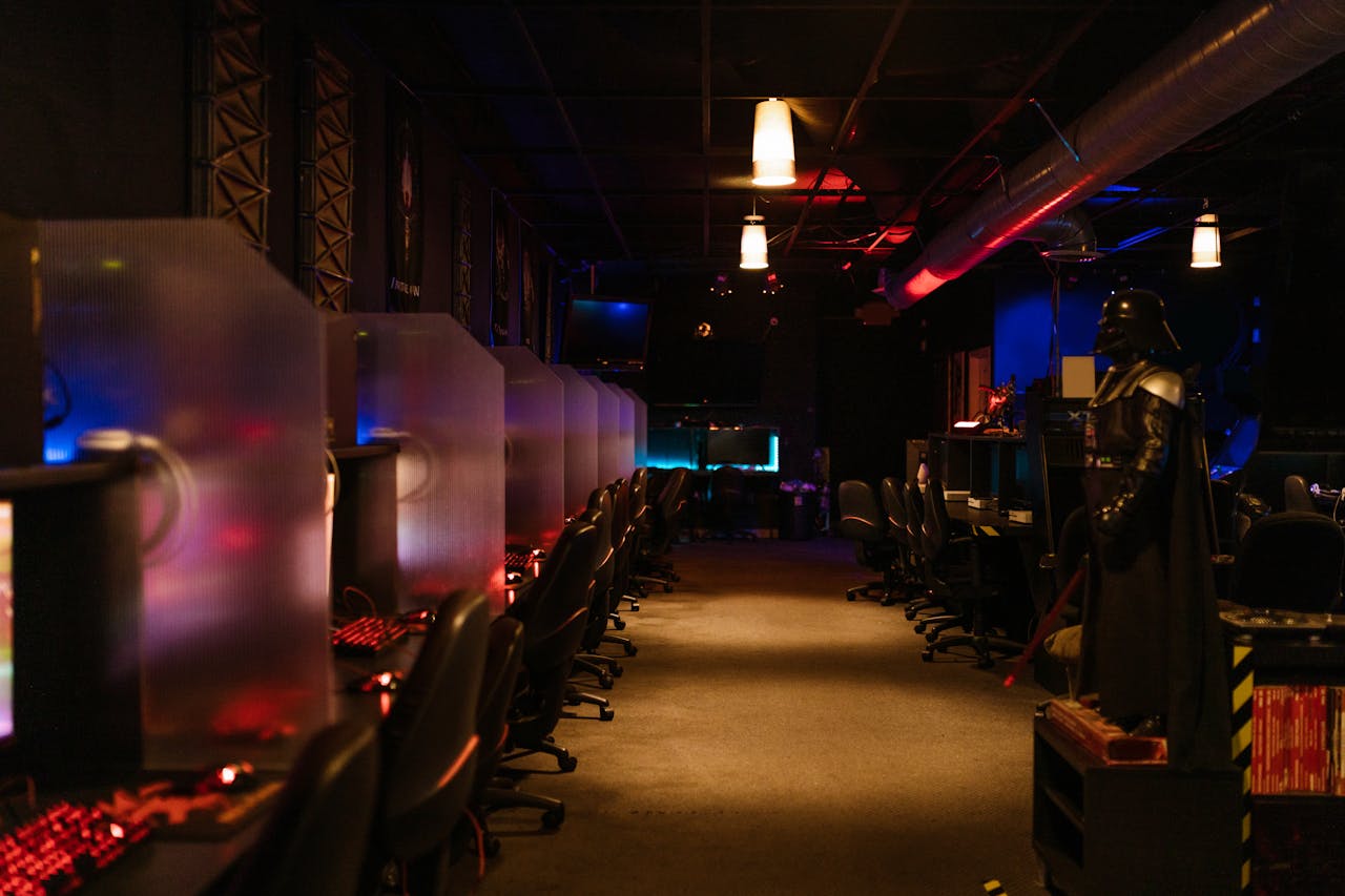 A dimly lit gaming arcade with neon lights and computers, creating a futuristic atmosphere.