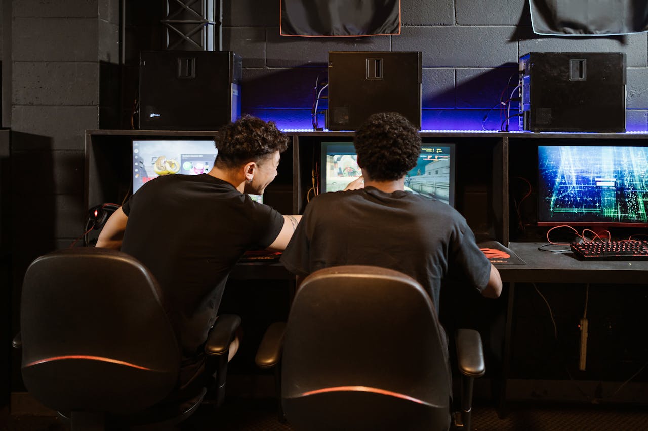 Two young men engaged in intense gaming session at an eSports venue. Computers and ambient lighting create an immersive experience.